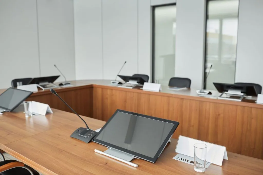 Spacious modern conference room with microphones and monitors on a wooden table
